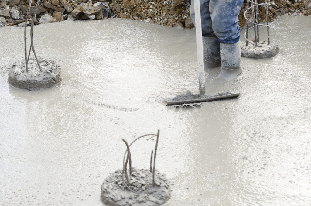 Concrete pouring and levelling during reinforced concrete frame construction on commercial building site